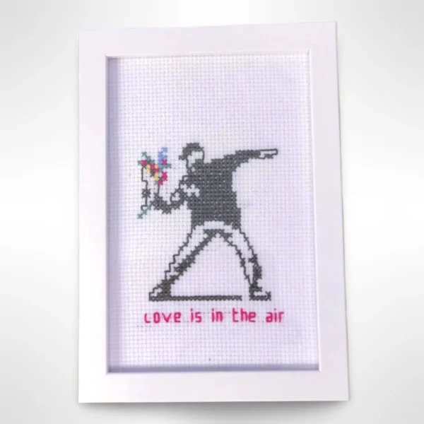 Håndlaget broderi inspirert av Banksys kunstverk "Love is in the Air". En unik dekorasjon for kunstelskere. Dimensjoner: 10 x 15 cm.